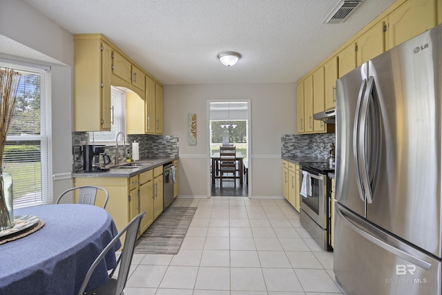 kitchen with under cabinet range hood, visible vents, a sink, backsplash, and stainless steel appliances
