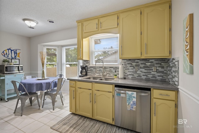 kitchen with a textured ceiling, light tile patterned floors, a sink, backsplash, and appliances with stainless steel finishes