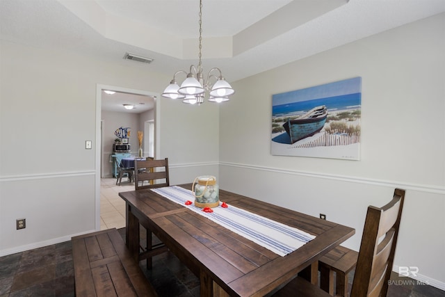 dining space featuring baseboards, a raised ceiling, a notable chandelier, and visible vents