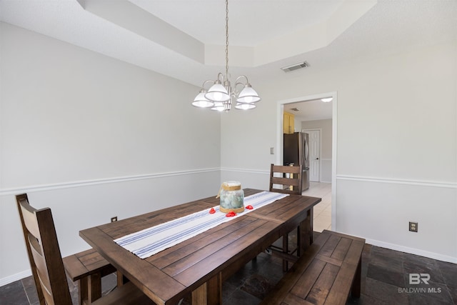 dining space with visible vents, baseboards, a raised ceiling, and a notable chandelier