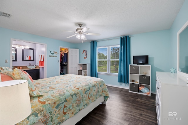 bedroom with a closet, a textured ceiling, visible vents, a spacious closet, and dark wood-style floors