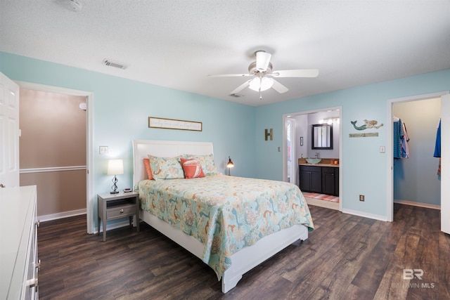 bedroom with dark wood finished floors, visible vents, baseboards, and a walk in closet