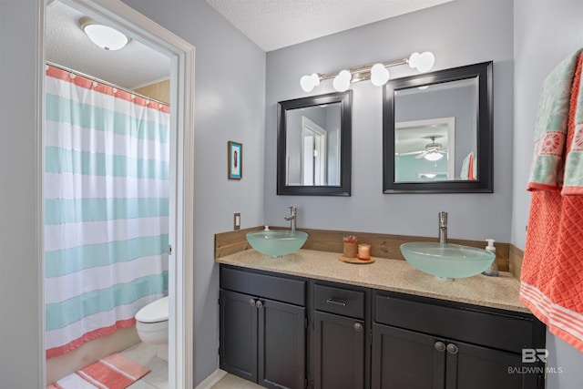 full bathroom with a sink, double vanity, a textured ceiling, and toilet
