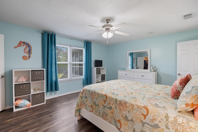 bedroom with a textured ceiling, baseboards, visible vents, and dark wood-style floors