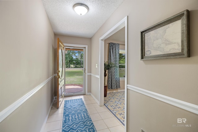 doorway featuring a textured ceiling, baseboards, and light tile patterned floors