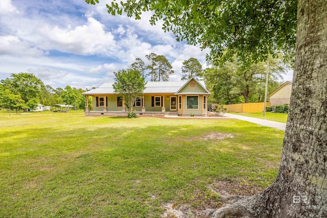 view of front facade featuring covered porch, metal roof, fence, and a front lawn