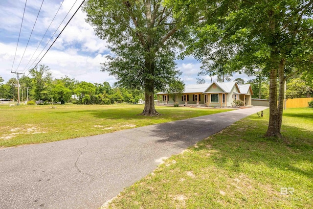 view of front of house featuring a front lawn, fence, and aphalt driveway
