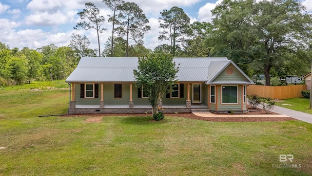 view of front of property with covered porch, metal roof, fence, and a front yard