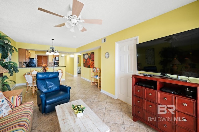 tiled living room featuring ceiling fan with notable chandelier and a textured ceiling