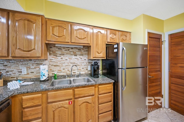 kitchen with backsplash, sink, dark stone countertops, light tile patterned floors, and appliances with stainless steel finishes