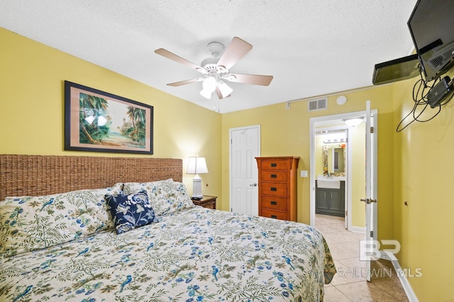 tiled bedroom featuring a textured ceiling, ensuite bath, ceiling fan, and sink