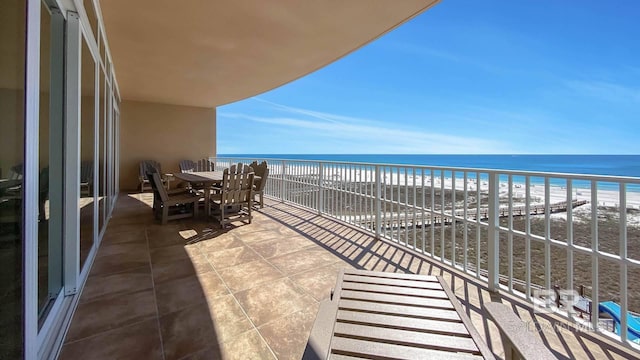 balcony featuring a view of the beach and a water view