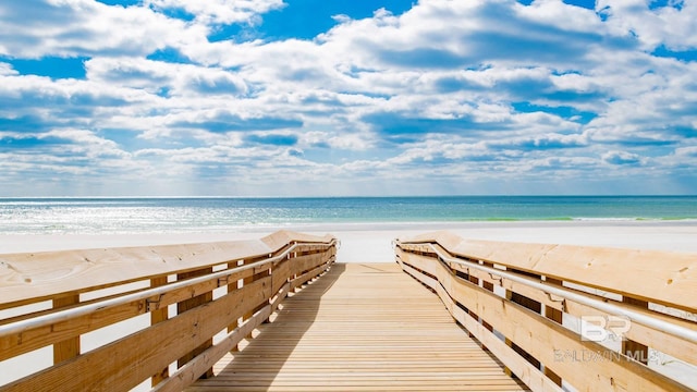 view of dock with a beach view and a water view