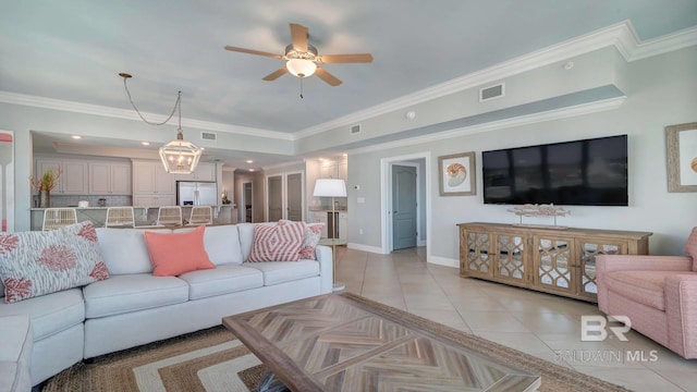 tiled living room with a tray ceiling, ornamental molding, and ceiling fan