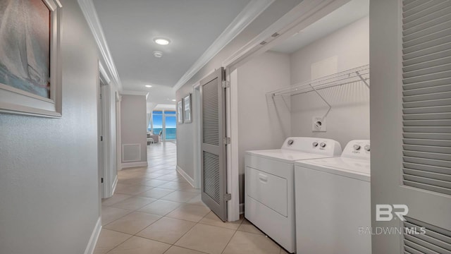 washroom featuring washer and dryer, crown molding, and light tile flooring