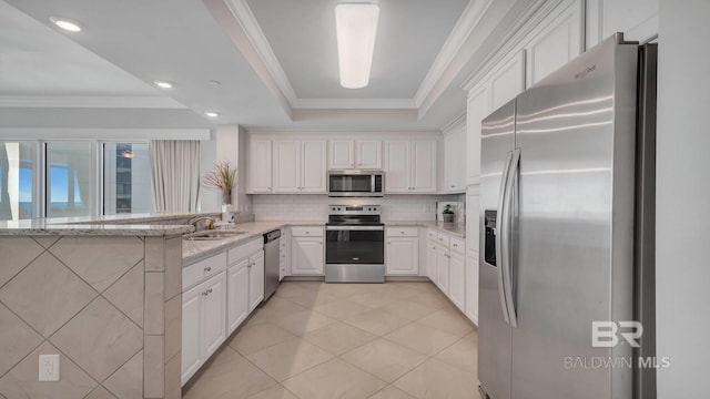 kitchen with light stone countertops, appliances with stainless steel finishes, white cabinets, kitchen peninsula, and sink