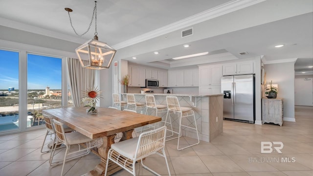 dining space featuring a tray ceiling, ornamental molding, an inviting chandelier, and light tile floors