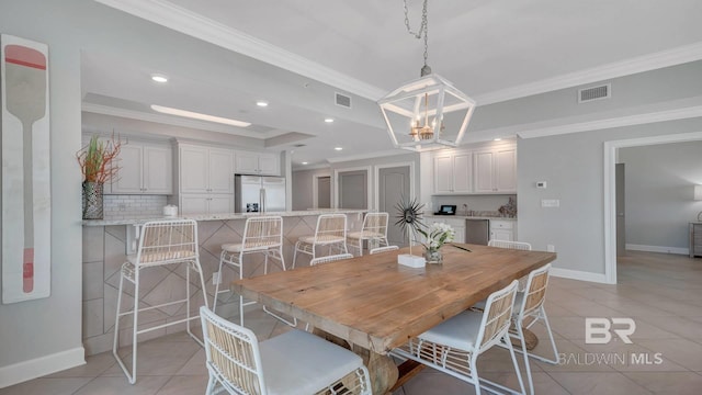 dining area featuring ornamental molding, a tray ceiling, a chandelier, and light tile floors