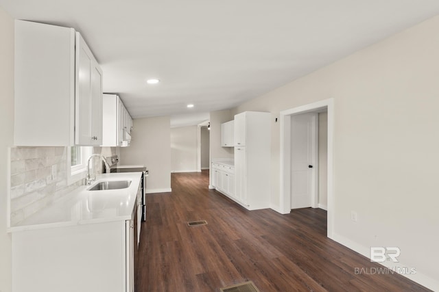kitchen with dark wood finished floors, light countertops, a sink, and white cabinets