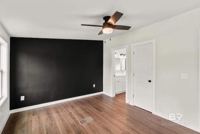 empty room featuring baseboards, visible vents, wood finished floors, and a ceiling fan