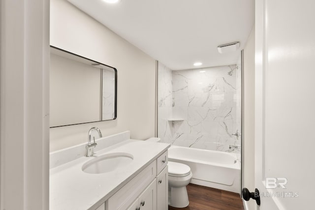 bathroom featuring toilet, vanity,  shower combination, and wood finished floors