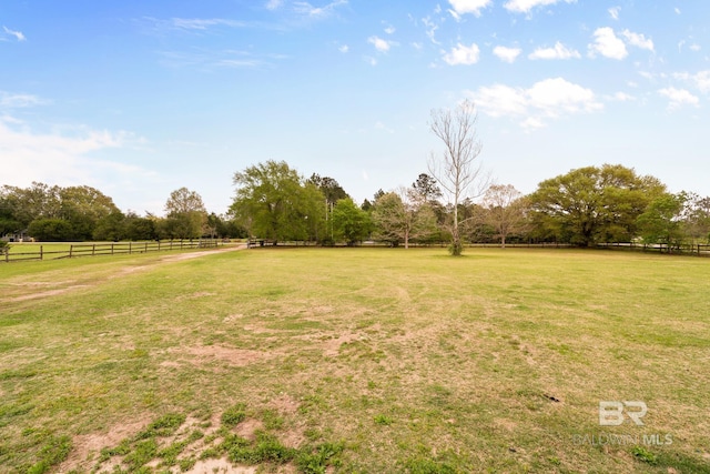 view of yard with fence and a rural view