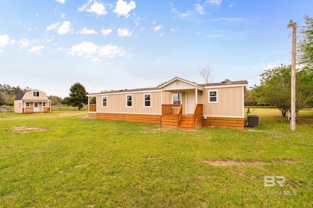 view of front of house with a front yard, central AC, and fence