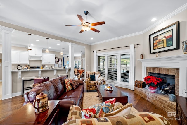 living room with ceiling fan, ornamental molding, dark hardwood / wood-style floors, and a brick fireplace