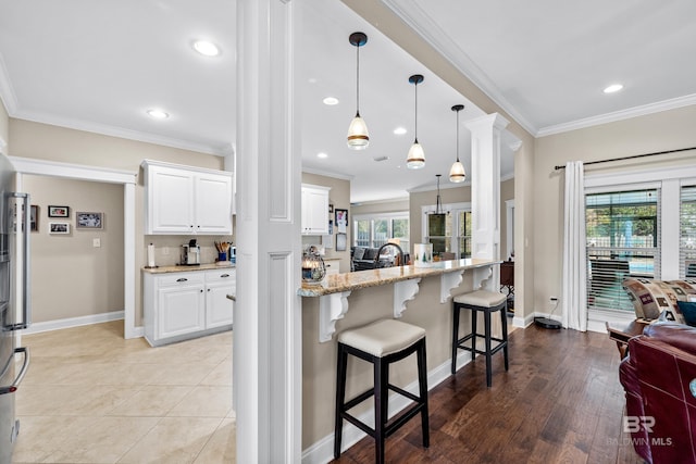 kitchen with light stone countertops, light wood-type flooring, white cabinetry, and plenty of natural light