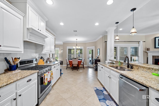 kitchen with white cabinets, stainless steel appliances, hanging light fixtures, and sink