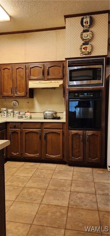 kitchen with stovetop, a textured ceiling, oven, and stainless steel microwave