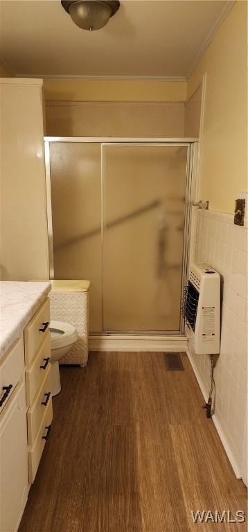 bathroom with hardwood / wood-style flooring, vanity, a shower with shower door, and heating unit