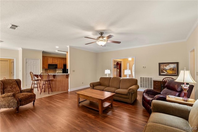 17174 Finnell Rd, Northport, AL 35475 - living room with dark wood finished floors, ceiling fan, visible vents, and ornamental molding