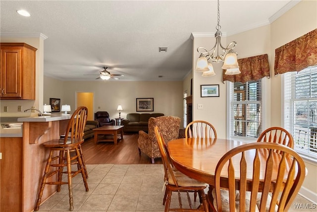 17174 Finnell Rd, Northport, AL 35475 - dining area with light tile patterned floors, visible vents, ceiling fan with notable chandelier, and crown molding