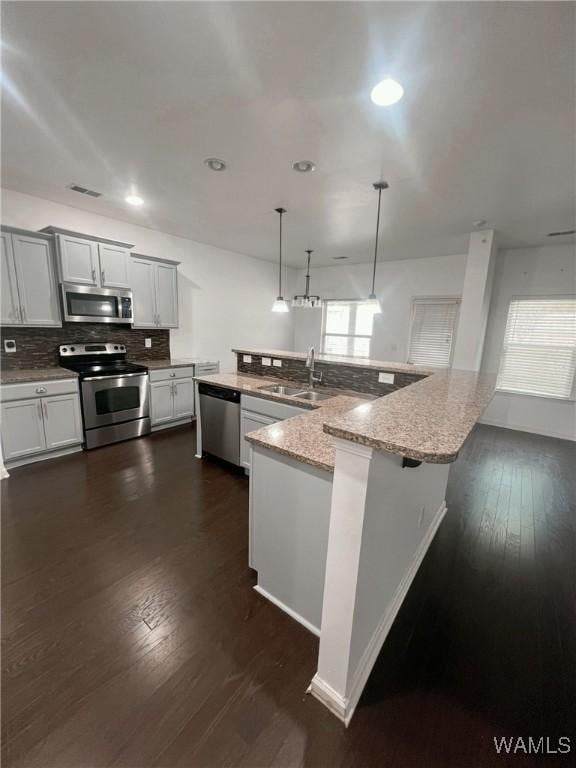 11507 Belle Meade Ave, Northport, AL 35475 - kitchen with appliances with stainless steel finishes, a sink, decorative backsplash, dark wood-style floors, and light stone counters