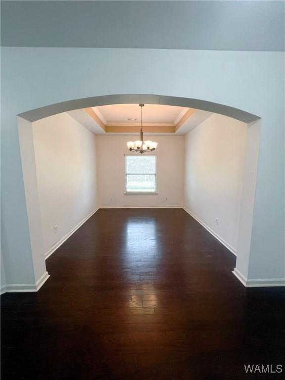 11507 Belle Meade Ave, Northport, AL 35475 - unfurnished room with a chandelier, arched walkways, dark wood-style floors, a tray ceiling, and baseboards