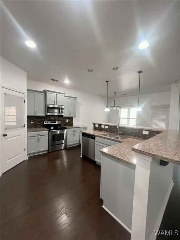 11507 Belle Meade Ave, Northport, AL 35475 - kitchen with appliances with stainless steel finishes, decorative backsplash, dark wood finished floors, light stone countertops, and a sink