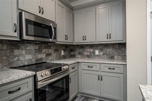 kitchen featuring gray cabinetry, light stone countertops, appliances with stainless steel finishes, and tasteful backsplash