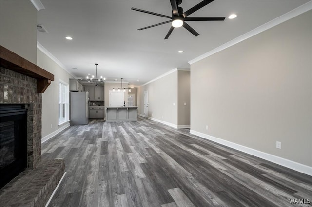 unfurnished living room featuring dark hardwood / wood-style floors, crown molding, and ceiling fan with notable chandelier