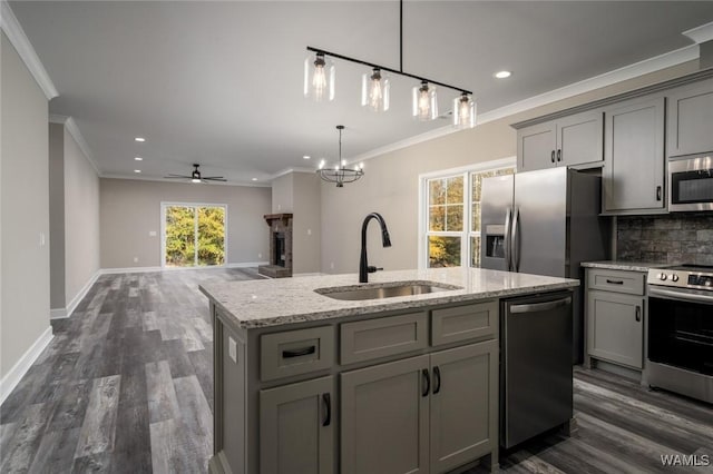 kitchen featuring a center island with sink, ceiling fan with notable chandelier, sink, gray cabinets, and appliances with stainless steel finishes