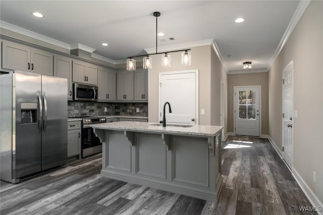 kitchen featuring a center island with sink, sink, ornamental molding, appliances with stainless steel finishes, and light stone counters