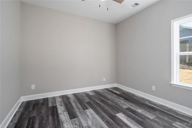 spare room featuring plenty of natural light, ceiling fan, and dark wood-type flooring