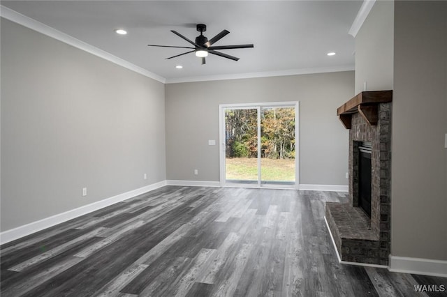 unfurnished living room with dark hardwood / wood-style flooring, a brick fireplace, and crown molding