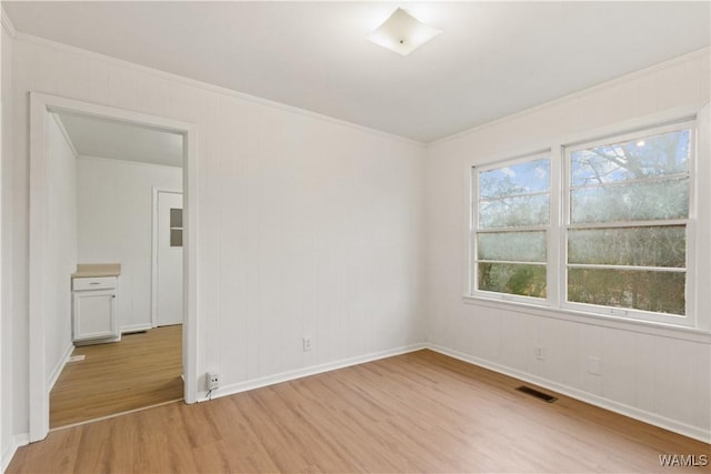 empty room with crown molding and light hardwood / wood-style flooring