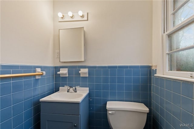 bathroom featuring vanity, tile walls, and toilet