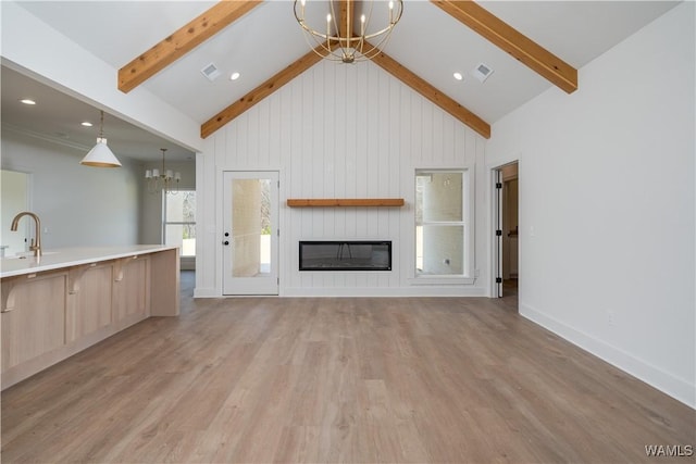 unfurnished living room with beamed ceiling, high vaulted ceiling, an inviting chandelier, and light hardwood / wood-style floors