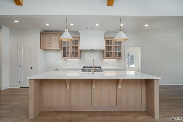 kitchen with a spacious island, light brown cabinetry, custom exhaust hood, and backsplash