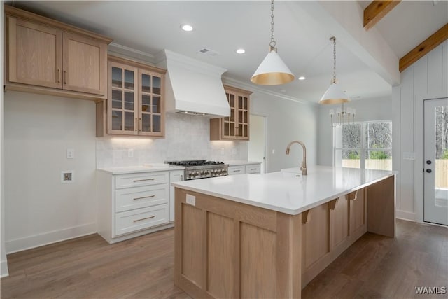 kitchen featuring pendant lighting, an island with sink, white cabinetry, decorative backsplash, and custom exhaust hood