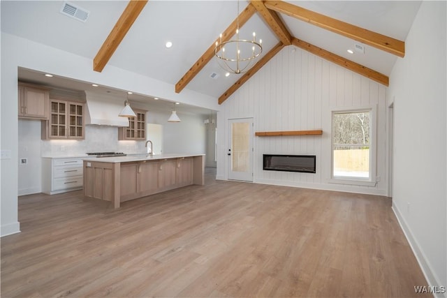 kitchen featuring beamed ceiling, a chandelier, light brown cabinets, pendant lighting, and a large island