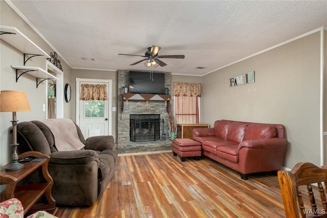 12569 Covered Bridge Rd, Brookwood, AL 35444 - living area featuring crown molding, ceiling fan, light wood-style floors, a textured ceiling, and a stone fireplace